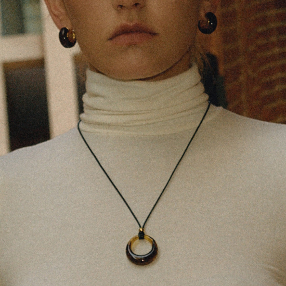 Amber-colored resin long necklace with a black cord. Vera Lux